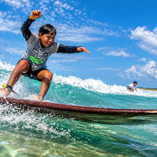 Young surfer riding a longboard through turquoise waves in the Galápagos Islands, Ecuador