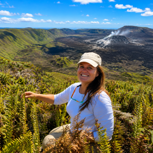 Galapagos naturalist exploring a volcanic landscape in the Galápagos with a steaming crater in the background