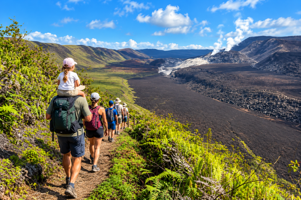 Hikers walking along the Sierra Negra Volcano trail overlooking a volcanic landscape on Isabela Island, Galápagos Caption: